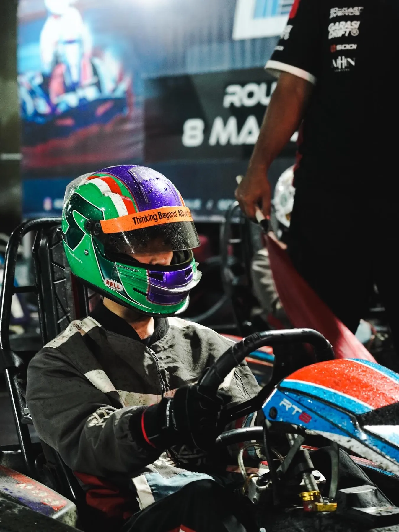 Putting on a green and purple helmet in the pit lane