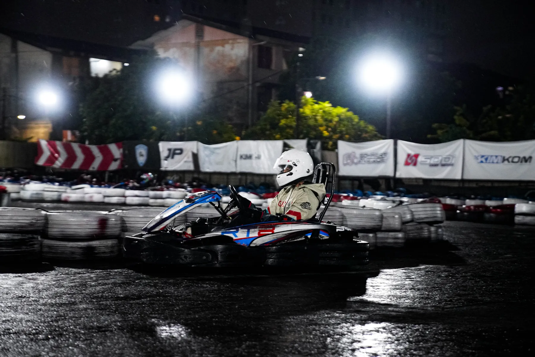 Karts lined up at the start grid in the rain at night