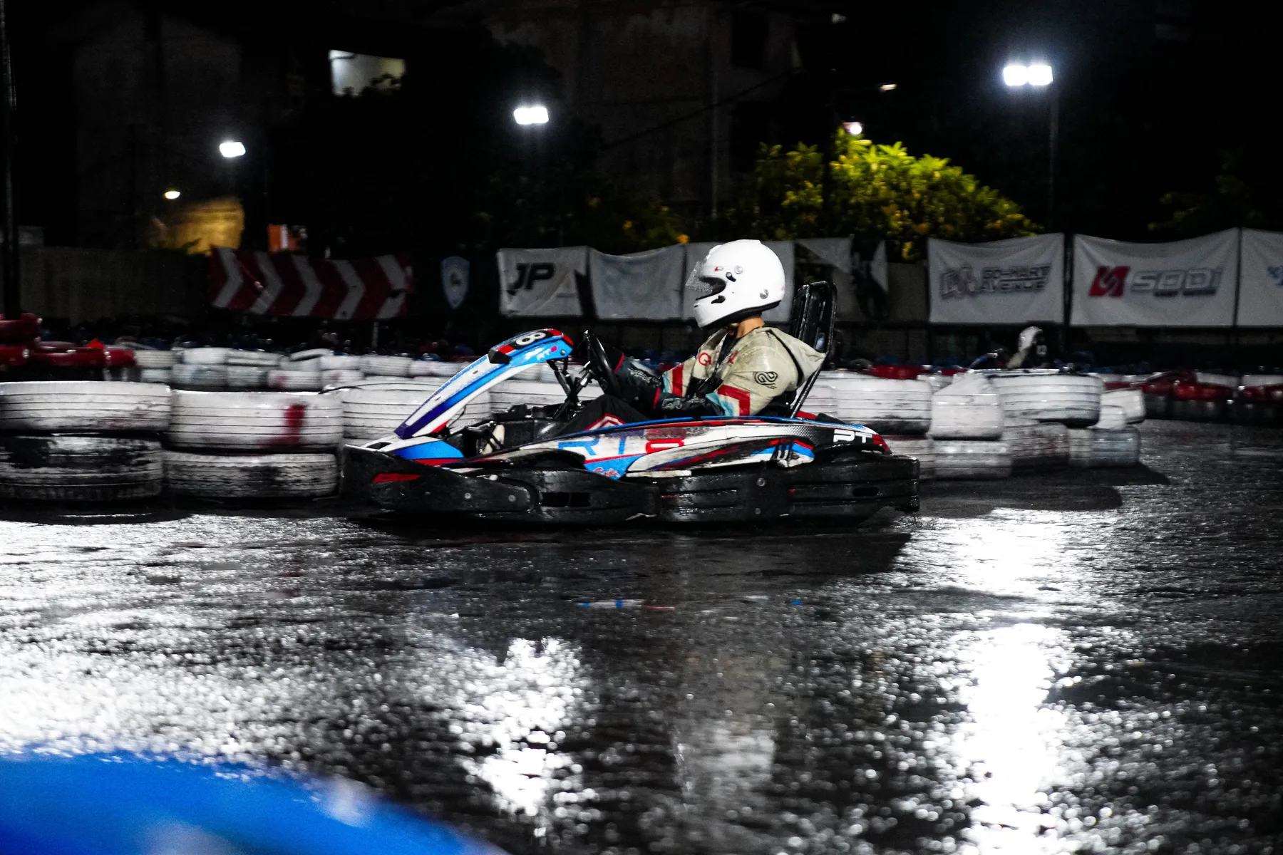 Kart racing under floodlights on a wet circuit at night